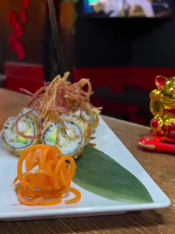 Katakana Roll servido en barra, con farolillos y maneki-neko de fondo